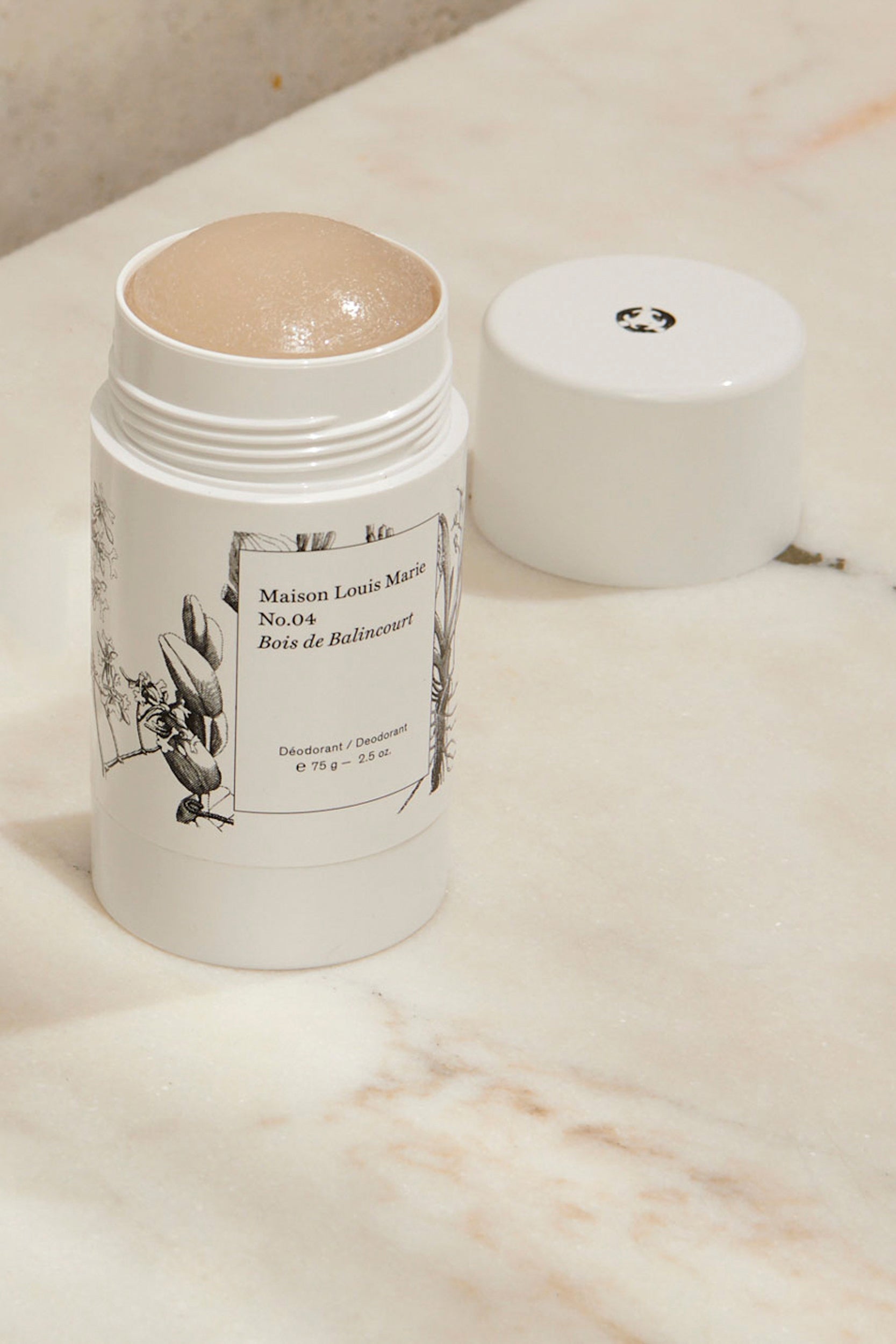 Deodorant with smell No. 04 Bois de Balincourt from Maison Louise Marie that has been opened. Standing on a marble table. 